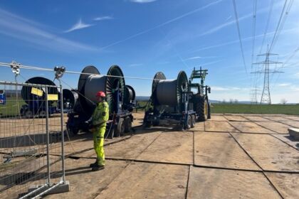 Cteam radnici postavljaju nove kablove za električnu mrežu uz pomoć velike opreme i koluta za kablove.