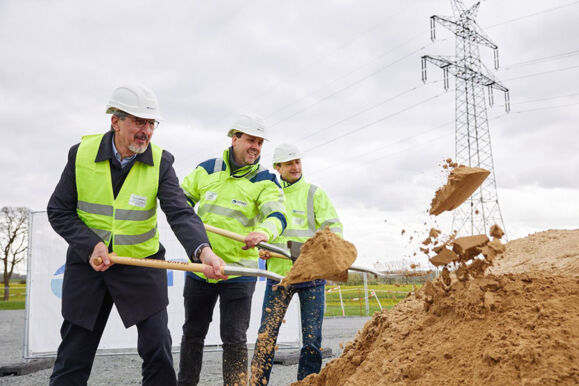 Spatenstich f&uuml;r ein Cteam Infrastrukturprojekt mit Strommasten im Hintergrund.