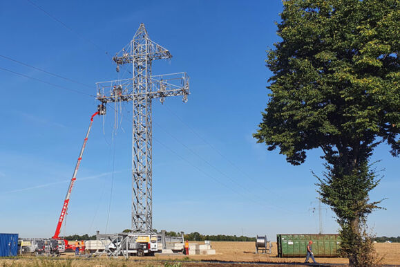Équipe Cteam effectuant des travaux de maintenance sur un pylône électrique avec une grue.