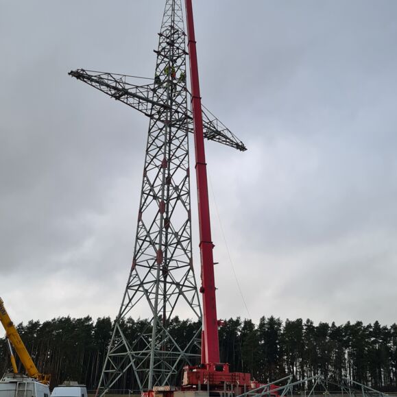 Grue Cteam montant une tour de transmission avec des techniciens travaillant en hauteur sur la structure m&eacute;tallique.