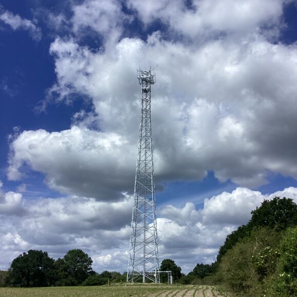 Cteam'in iletişim kulesi, bulutlu bir g&ouml;ky&uuml;z&uuml; altında tarımsal bir alanda yer almaktadır.
